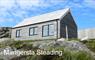 Mangersta Steading a larch clad cottage with three large windows and corrugated roofing sits on a rocky hillside at Mangersta Croft Holidays.