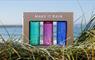 North Uist Distillery Downpour mini gin gift set, on grass, overlooking the sea.