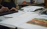 Close up photo of someone working in the print workshop with books and art work materials.