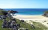 Mangersta Beach, Isle of Lewis on a sunny summer's day. A white sandy cove is bounded by green rocky promontories and a blue ocean.