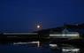 Photo of Taigh Chearsabhagh taken on a dark moonlit evening, showing the tide line lighting installation round the building.