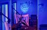 Photo of bagpipes placed on a chair, with the Taigh Chearsabhagh logo in blue lighting behind.