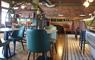 HS1 cafe bar interior with table and charis in a tan and teal colourway and exposed brick wall at rear.