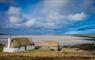 Traditional thatched, white washed cottage in North Uist in the Outer Hebrides. House sitting close to the shoreline with large sandy beach.