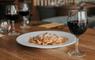 Plate of pasta and a glass of wine set on a table