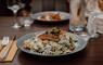 Scottish pan fried salmon, risotto dish on a set table with cutlery and wine glasses.