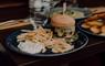 Homemade burger on a bun with chips on a plate.