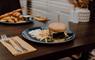 A larger burger with cheese and homemade bun, with a side of fires, all presented on a table at Cleaver at the Cabarfeidh.