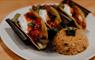 Three roasted vegetable tacos with rice and sauce on a white plate.