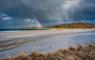 The Croft House beach with dark clouds and rainbow