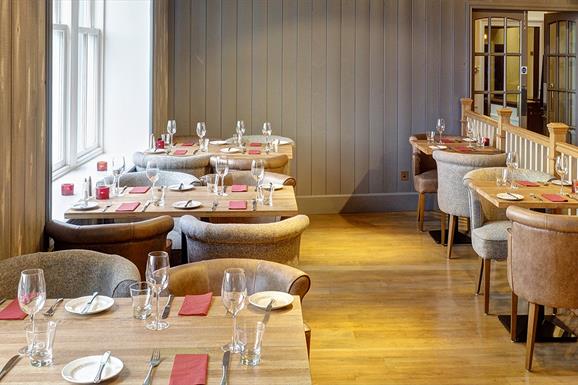 The Boatshed restaurant at The Royal Hotel, restaurant with wooden flooring, wooden tables with tan leather chairs, grey panelling on walls.