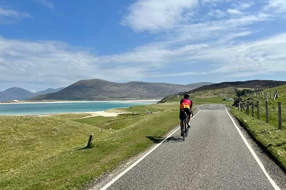 Cyclist passing beach in Harris