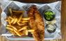 The Boatshed restaurant at The Royal Hotel, fish and chips set on a plate with tartare sauce and mushy peas, sitting on a wooden table.