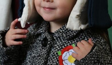 A picture of a young child in a coat wearing a Tudor hat and a Tudor rose badge