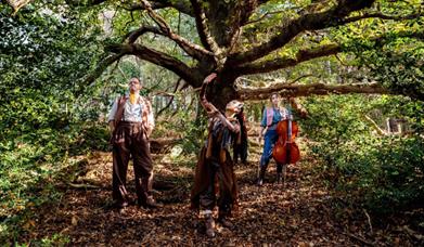 Three people walking through and dancing in a forest.