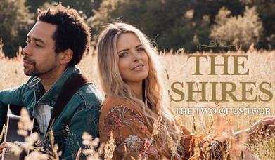 Image of the Shires sitting in a field. Text reads: The Shires, the Two of Us tour.