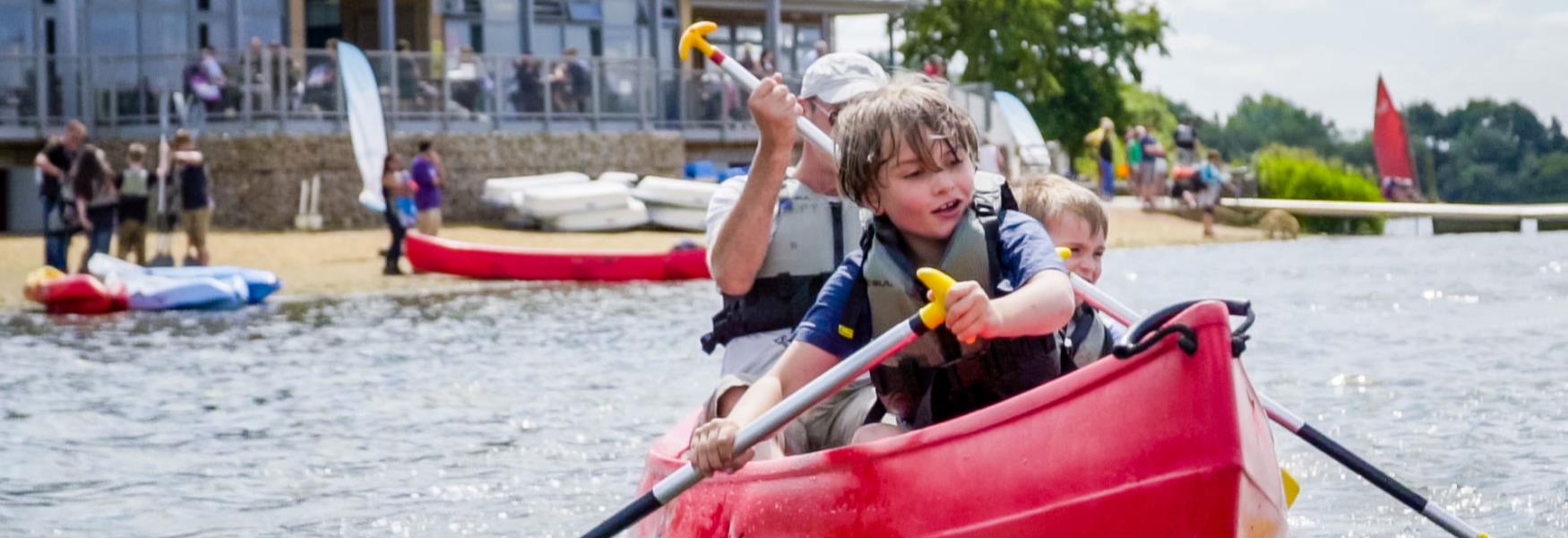 A boy and his family canoeing at Ferry Meadows in Nene Park.