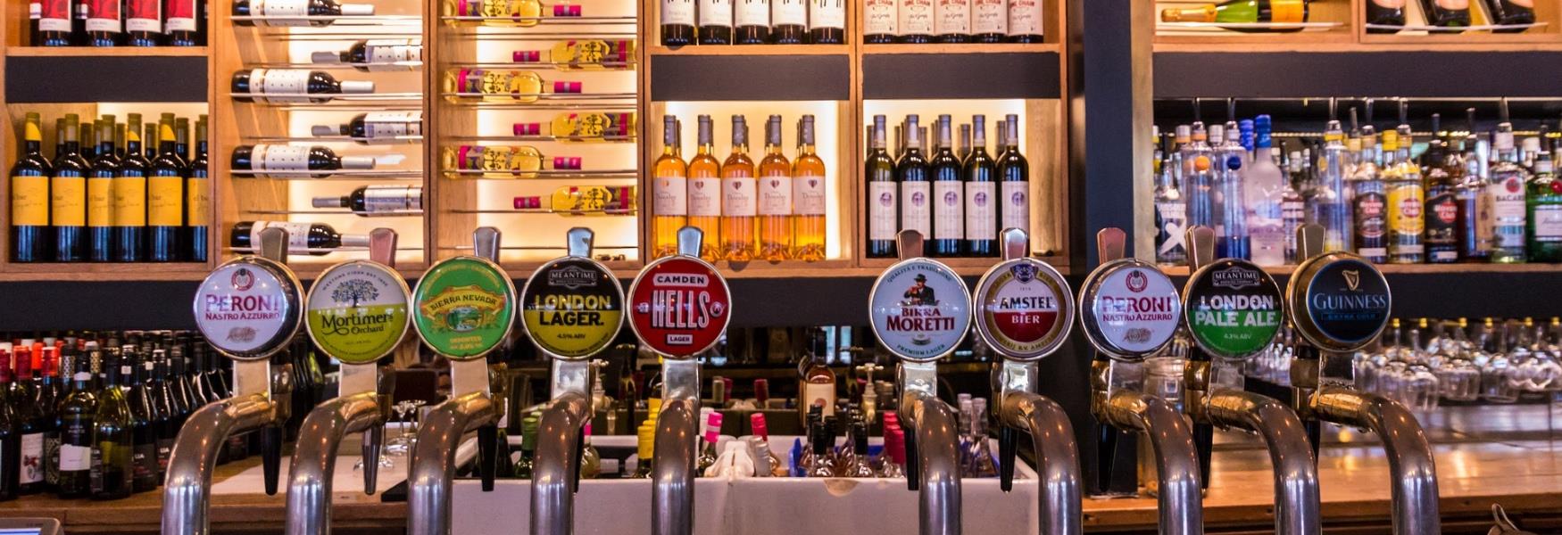 Image of a pub bar with a selection of beverages and beer pumps