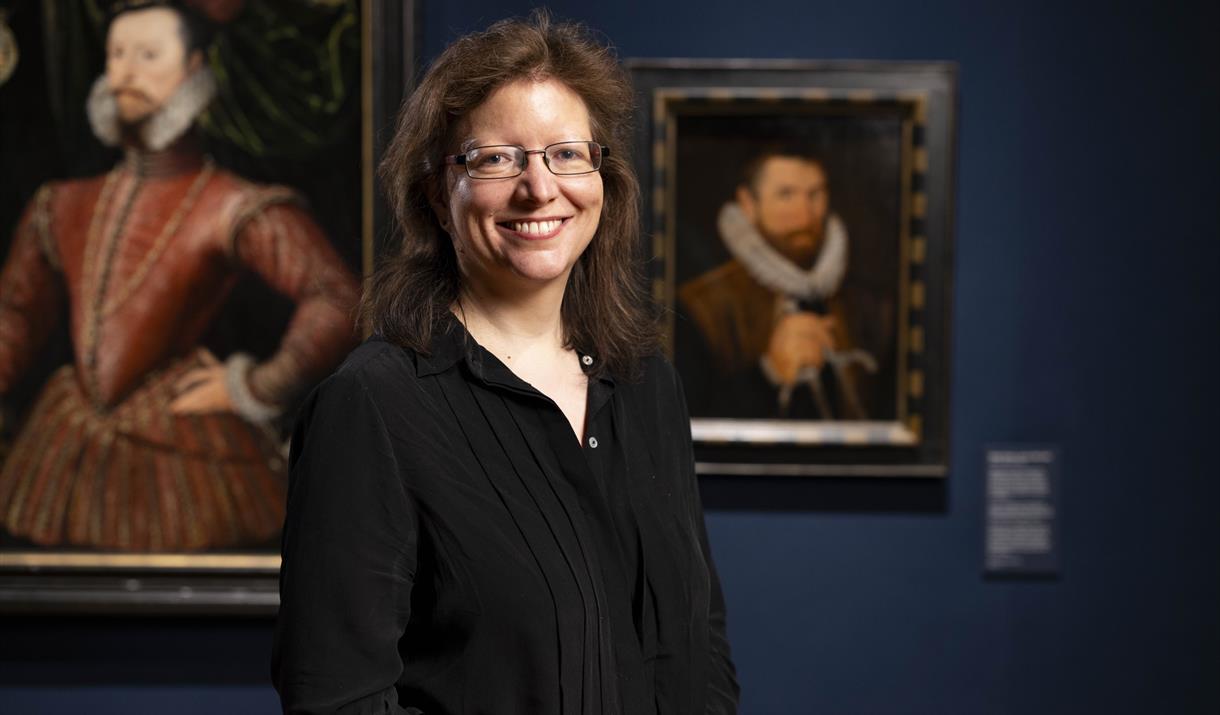 A photograph of Dr Charlotte Bolland standing formally in a art gallery