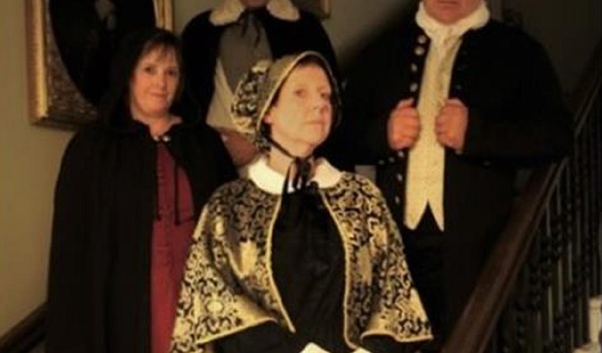 Costumed tour guides standing on Peterborough Museum staircase