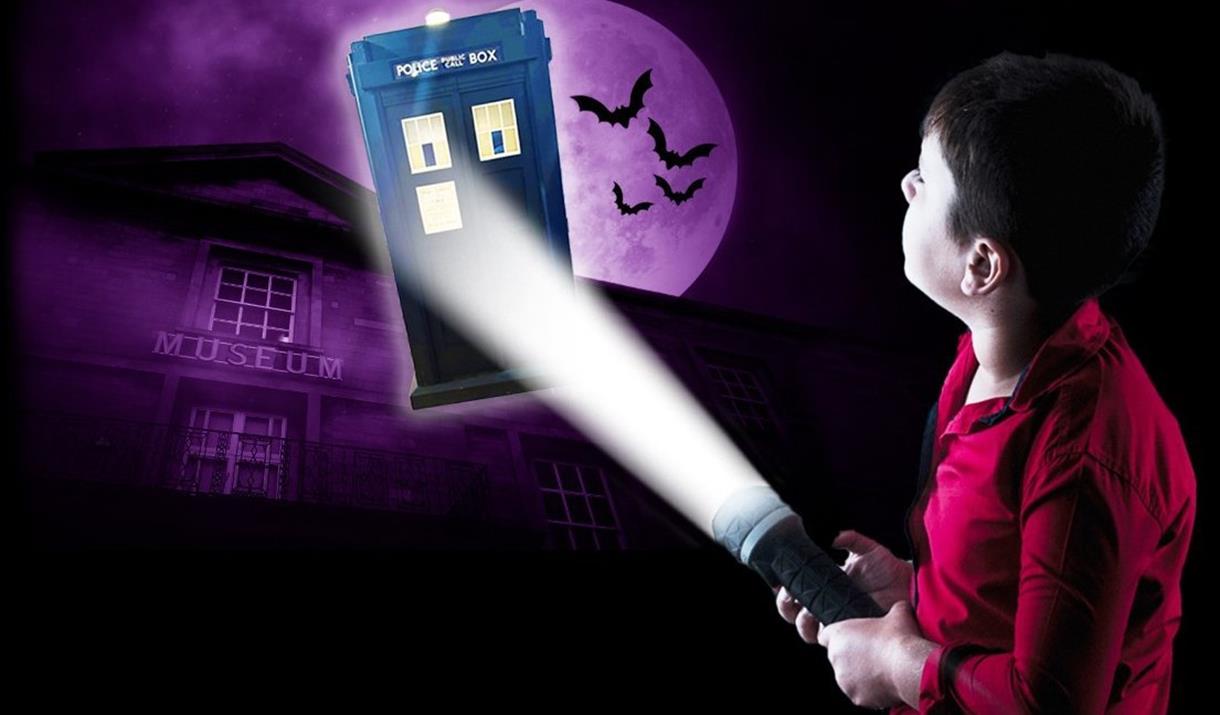 A child pointing a torch at the TARDIS, which flies in front of the Peterborough Museum.