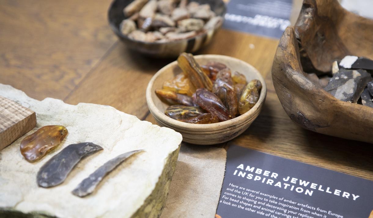 Materials to make Bronze Age jewellery laid out on a table, including amber