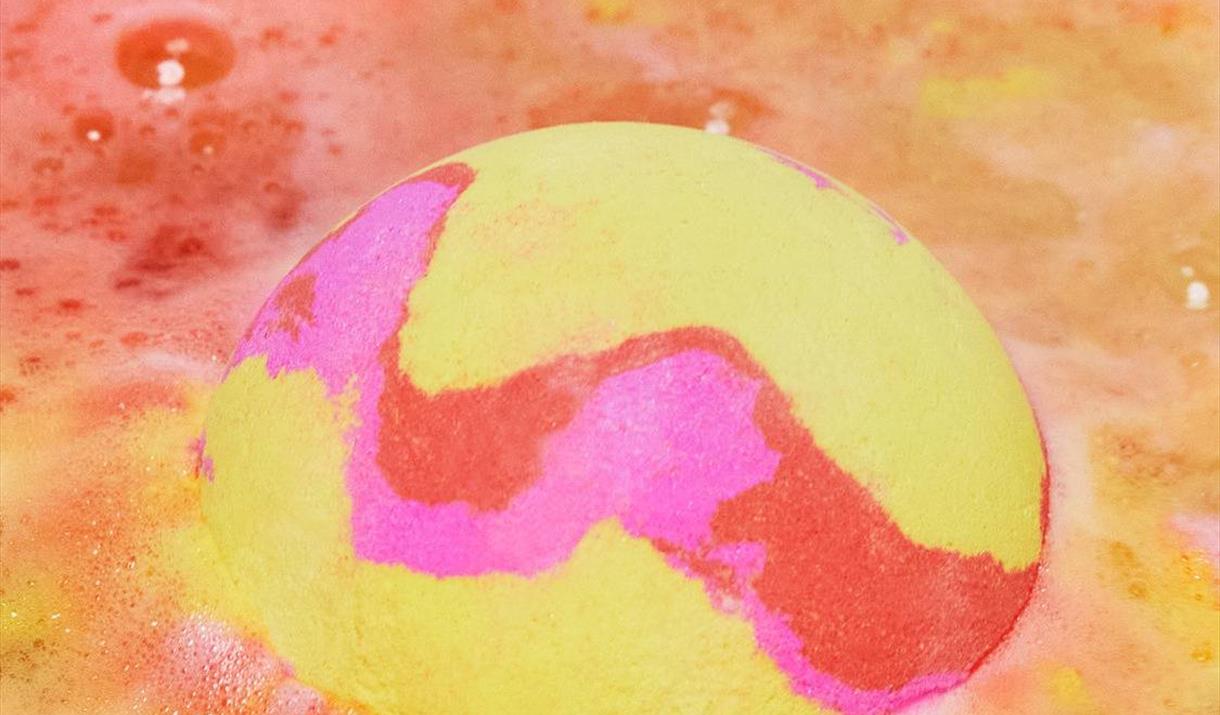A yellow and pink bath bomb in water