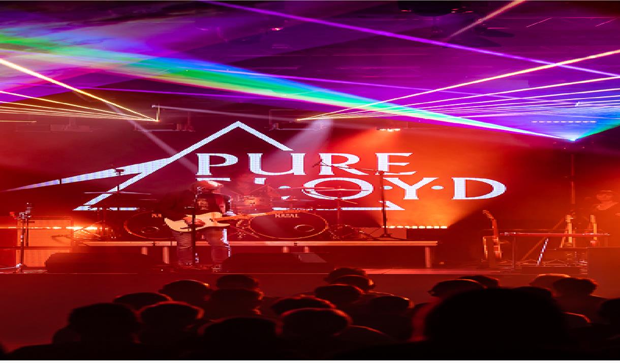 A concert with red and neon lighting. Logo of a triangle with the words 'Pure Floyd'.