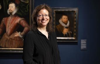 A photograph of Dr Charlotte Bolland standing formally in a art gallery