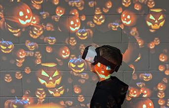 little boy with vr headset on and pumpkin background.