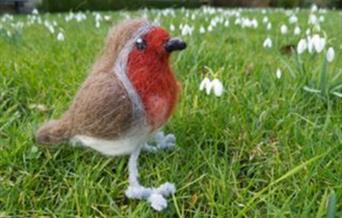 Close up of a needle felted robin in a grassed area