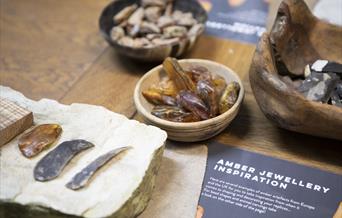 Materials to make Bronze Age jewellery laid out on a table, including amber