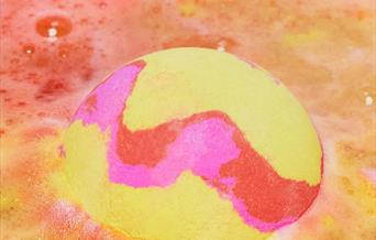 A yellow and pink bath bomb in water