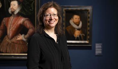 A photograph of Dr Charlotte Bolland standing formally in a art gallery