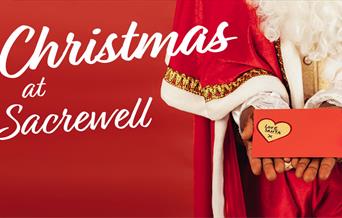 Christmas at Sacrewell - Santa holding gift.
