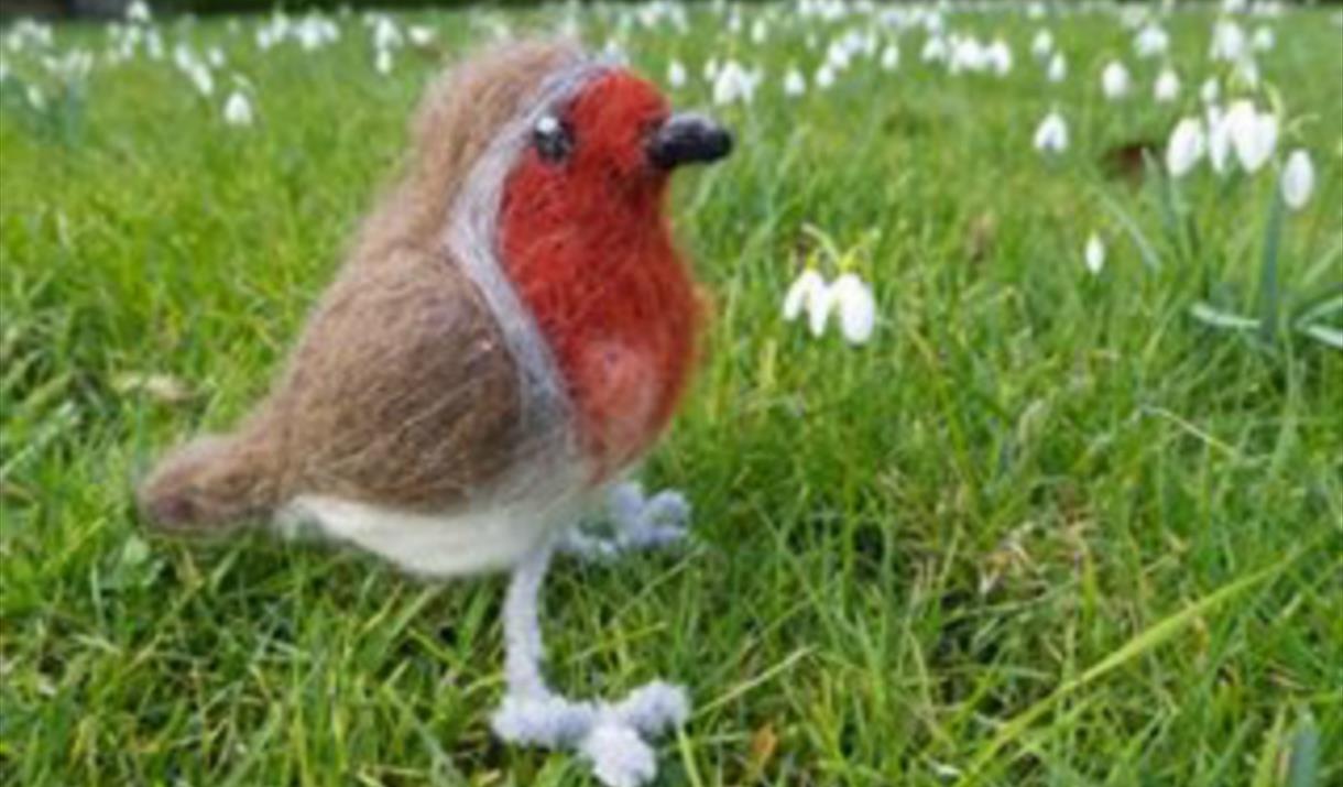 Close up of a needle felted robin in a grassed area