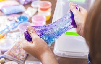 child's hands pulling apart purple slime