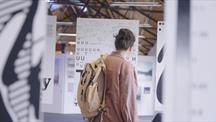 Person wearing a backpack viewing typography displays at an exhibition.