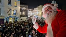 Crowds of people with a Santa waving in the foreground 