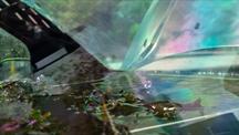 A close-up view through curved glass panels of a water-filled marine exhibit, with seaweed and shimmering green, blue and pink reflections.