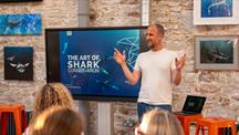 A man stood in front of a group of people doing a presentation on sharks 