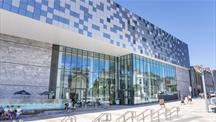 Exterior of the Box, Plymouth's Museum. It shows a large silver reflective building with people walking outside of it. 