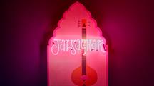 A photograph of a pink neon light spelling out the name of the exhibition Jalsaghar