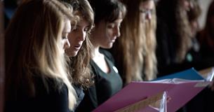 Choir members singing from sheet music