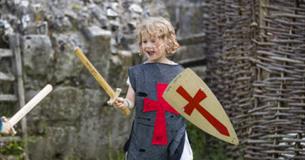 Young child dressed as a Medieval knight holding a toy sword