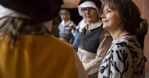 A volunteer talking to visitors in Buckland Abbey's historic kitchen