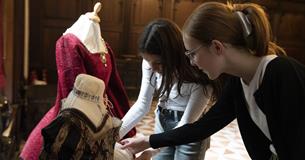Two people looking at a Tudor dress displayed on a mannequin