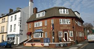 The red brick exterior of the West Hoe, situated on a street corner with the Port o Call Café next door.