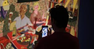 a person taking a picture of grayson perry's tapestries