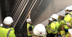 A group in high visibility jackets listen to a mad talking within the anchorage chamber